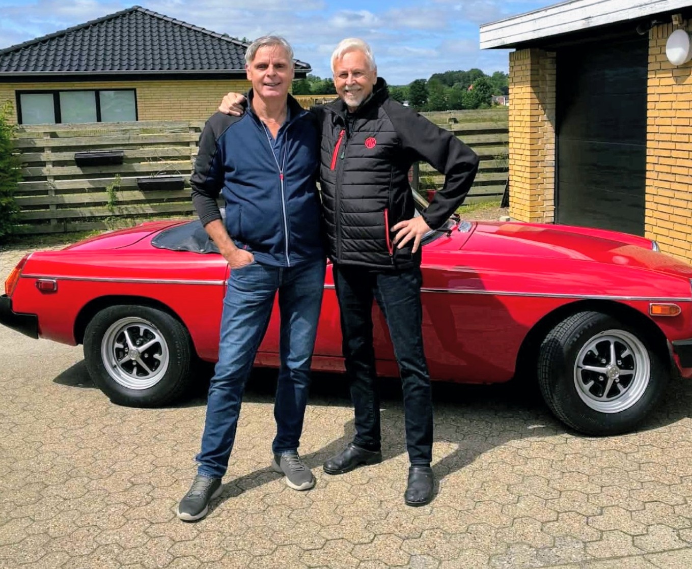 MGB 1978 Rød klassisk bil ved en gårdbygning.